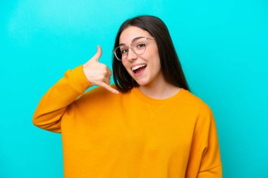 Mavi arka planda gözlüklü ve telefon hareketleriyle izole edilmiş genç bir kız.