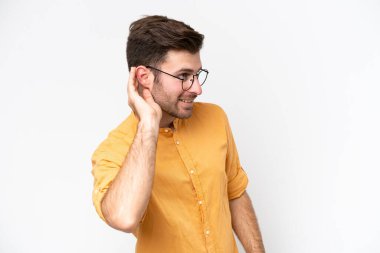 Beyaz arka planda izole edilmiş genç beyaz bir adam. Kulağına elini sürerek bir şeyler dinliyor.