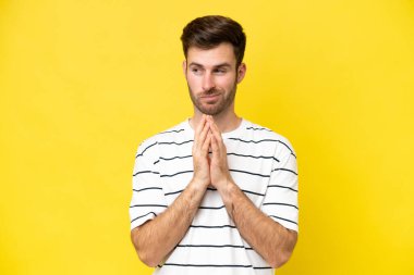 Genç beyaz adam sarı arka planda izole edilmiş bir şeyler çeviriyor.