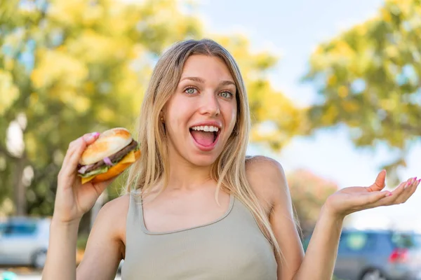 Junge Blonde Frau Hält Mit Schockiertem Gesichtsausdruck Einen Burger Freien — Stockfoto