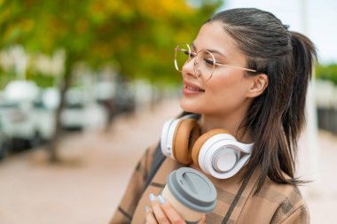 Dışarıdaki güzel kadın elinde kahve tutuyor.