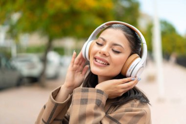 Açık havada müzik dinleyen genç ve güzel bir kadın.