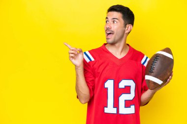 Sarı arka planda ragbi oynayan yakışıklı genç adam çözümü bulmak için parmağını kaldırıyor.