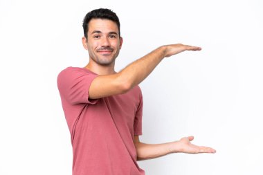 İzole edilmiş beyaz arka plan üzerinde genç yakışıklı bir adam reklam koymak için kopyalama alanı tutuyor