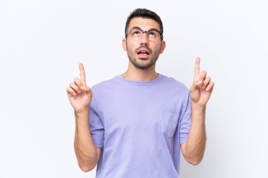 Beyaz arka planda izole edilmiş genç beyaz adam şaşırmış ve yukarı bakıyor.