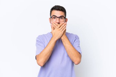 Beyaz arka planda izole edilmiş genç beyaz bir adam elleriyle ağzını kapatıyor.
