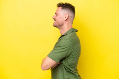 Beyaz tenli yakışıklı adam, sarı arka planda yalıtılmış, yan pozisyonda.