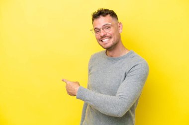 Sarı arka planda izole edilmiş beyaz, yakışıklı genç bir adam.