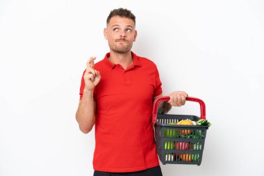 Beyaz arka planda izole edilmiş, elinde yiyecek dolu bir sepet tutan genç beyaz bir adam.