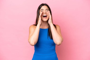 Genç Brezilyalı bir kadın pembe arka planda izole edilmiş bağırıyor ve bir şeyler söylüyor.