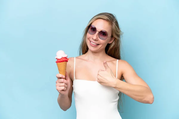 何か良いことが起こったので 青い背景に隔離されたアイスクリームを保持する水着の若い金髪の女性 — ストック写真