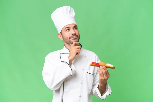 Jovem Chef Caucasiano Segurando Sushi Sobre Fundo Isolado Olhando Para — Fotografia de Stock