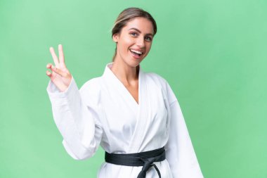 Genç Uruguaylı kadın tecrit edilmiş arka planda karate yapıyor. Gülümsüyor ve zafer işareti gösteriyor.