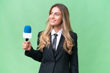 Genç, güzel Uruguaylı televizyon sunucusu izole edilmiş arka planda yan tarafa bakıyor ve gülümsüyor.