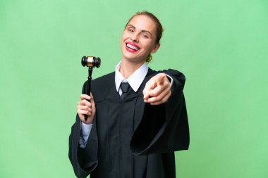 İzole edilmiş geçmişi olan beyaz bir kadın, mutlu bir ifadeyle ön tarafı işaret ediyor.