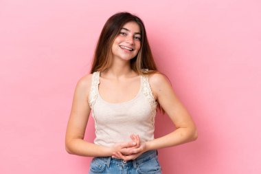 Pembe arka planda izole edilmiş genç beyaz kadın gülüyor.