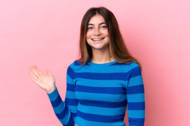 Pembe arka planda izole edilmiş genç beyaz kadın bir fikir sunuyor ve gülümsüyor.