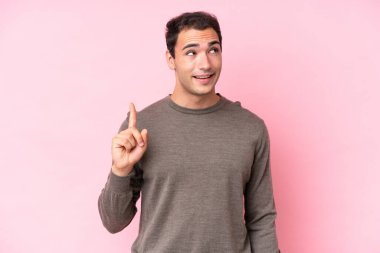 Pembe arka planda izole edilmiş genç beyaz adam çözümü bulmak için parmağını kaldırıyor.