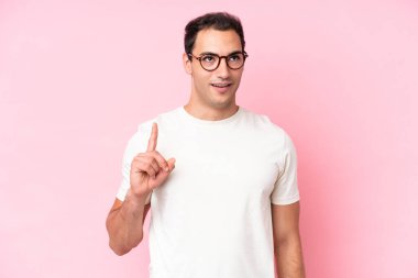 Pembe arka planda izole edilmiş genç beyaz bir adam bir fikri işaret ederek...
