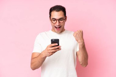 Pembe arka planda izole genç beyaz adam şaşırdı ve bir mesaj gönderiyor.