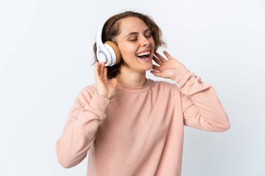 Genç İngiliz kadın beyaz arka planda izole edilmiş müzik dinliyor ve şarkı söylüyor.