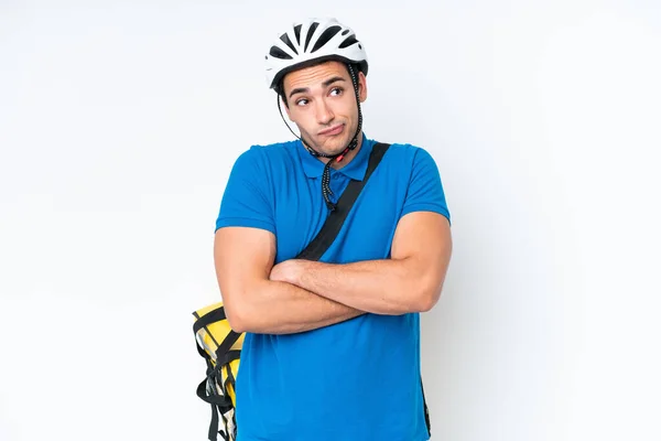 stock image Young caucasian man with thermal backpack isolated on white background making doubts gesture while lifting the shoulders