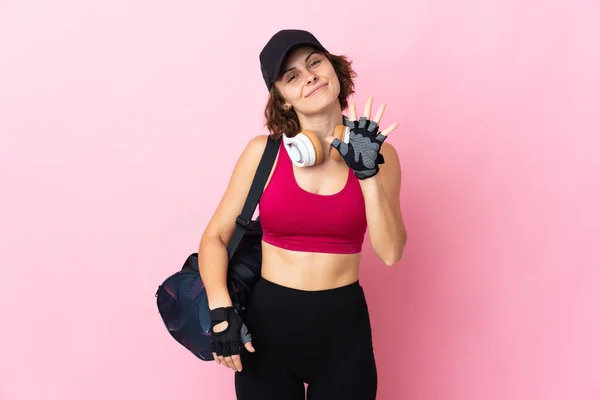 Young sport woman with sport bag over isolated background counting five with fingers
