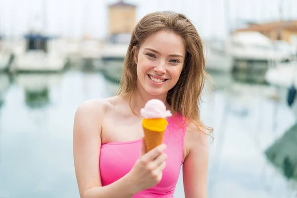 Young redhead woman with a cornet ice cream at outdoors with happy expression