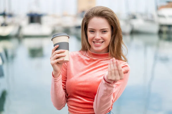 年轻的红头发女人在户外拿着一杯咖啡 邀她来手拉手 很高兴你来了 — 图库照片