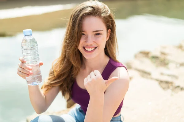 Jonge Roodharige Vrouw Met Een Fles Water Buiten Wijzend Naar — Stockfoto