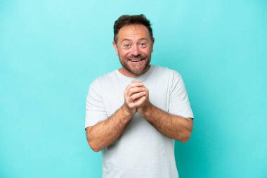 Orta yaşlı beyaz bir adam mavi arka planda izole edilmiş gülüyor.