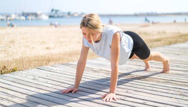 Açık havada yoga yapan genç sarışın kadın.