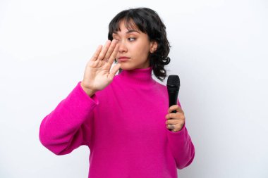 Genç Arjantinli şarkıcı kadın beyaz arka planda izole edilmiş. Durma hareketi yapıyor ve hayal kırıklığına uğruyor.