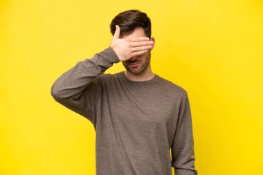 Sarı arka planda, gözleri elle kapatan genç beyaz bir adam. Bir şey görmek istemiyorum.