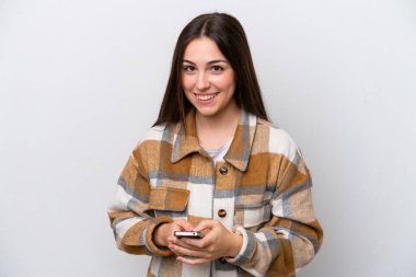 Beyaz arka planda izole edilmiş genç bir kız cep telefonuyla mesaj gönderiyor.