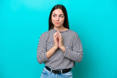 Kafkasyalı genç bir kadın mavi arka planda bir şeyler planlıyor.