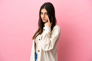 Pembe arka planda izole edilmiş beyaz bir kadın bir şey gösteriyor.