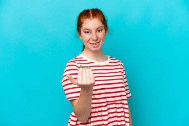 Mavi arka planda izole edilmiş genç, kırmızımsı bir kadın bizi davet ediyor. Gelmene sevindim.