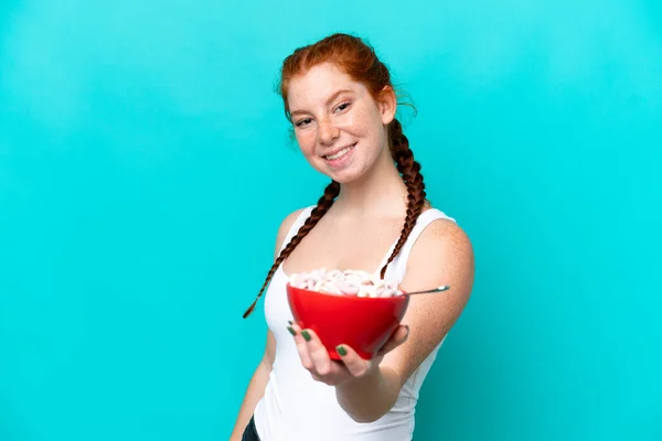 Młoda Rudowłosa Kobieta Trzyma Miskę Zbóż Niebieskim Tle Szczęśliwym Wyrazem — Zdjęcie stockowe
