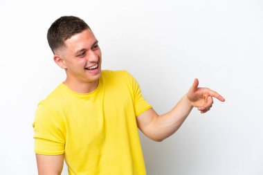 Beyaz arka planda izole edilmiş genç Brezilyalı bir adam parmak göstererek bir ürün sunuyor.