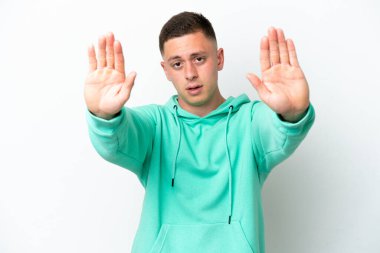 Beyaz arka planda izole edilmiş genç Brezilyalı adam dur hareketi yapıyor ve hayal kırıklığına uğruyor.