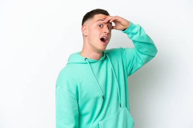 Beyaz arka planda izole edilmiş genç Brezilyalı adam yan tarafa bakarken sürpriz jest yapıyor.