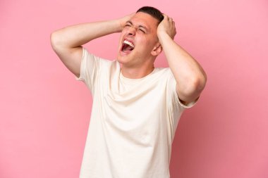 Pembe arka planda izole edilmiş genç Brezilyalı adam bunalımda.