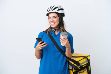 Young delivery woman with thermal backpack isolated on white background holding coffee to take away and a mobile