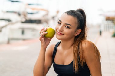 Açık havada elinde elma tutan güzel bir kadın.