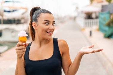 Açık havada kornet dondurması olan genç ve güzel bir kadın. Suratı şaşırmış.