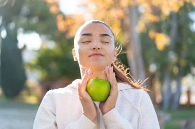 Elma tutan genç ve güzel bir bayan.