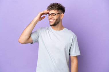 Delivery caucasian man isolated on purple background smiling a lot