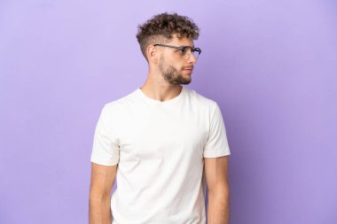 Mor arka planda izole edilmiş beyaz adam yan tarafa bakıyor.