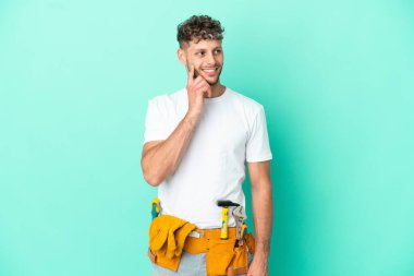Genç elektrikçi sarışın adam yeşil arka planda izole edilmiş bir şekilde bakarken bir fikir düşünüyor.